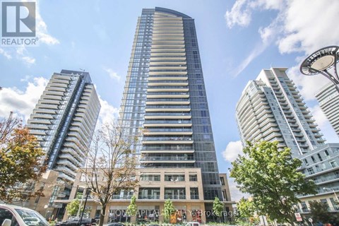 A tall building with a glass facade stands in the center of a city street.
