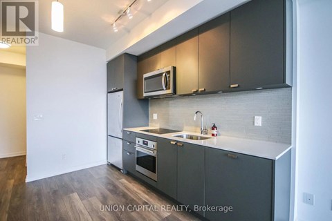 A kitchen with dark grey cabinets and a white countertop.