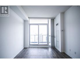 A spacious room with a large window and wooden flooring.