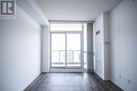 A spacious room with a large window and wooden flooring.