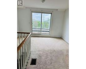 A room with a carpeted floor and a wooden staircase.