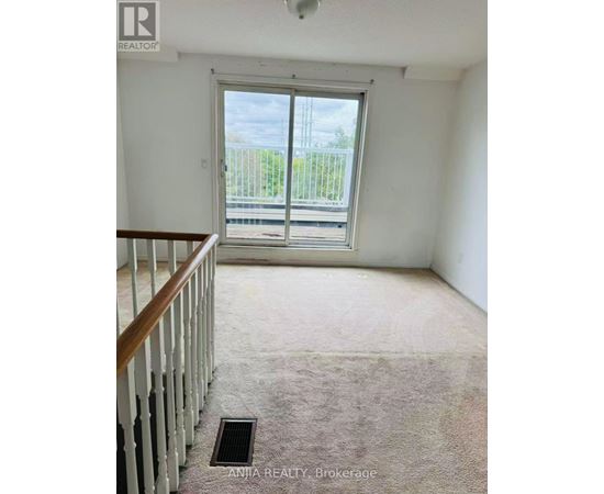 A room with a carpeted floor and a wooden staircase.