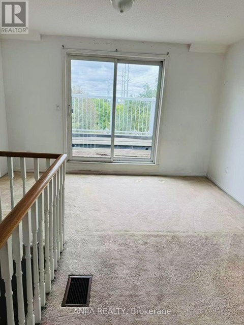 A room with a carpeted floor and a wooden staircase.
