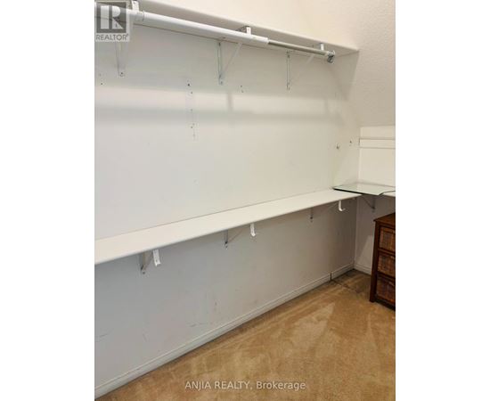 A white wall with hooks and a wooden cabinet.