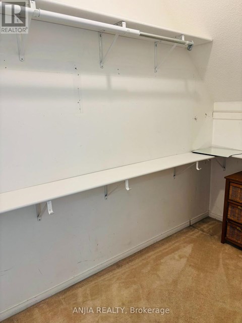 A white wall with hooks and a wooden cabinet.