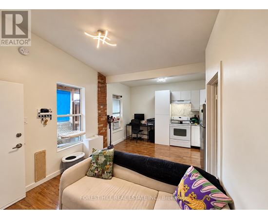 A living room with a couch and a kitchen area in the background.