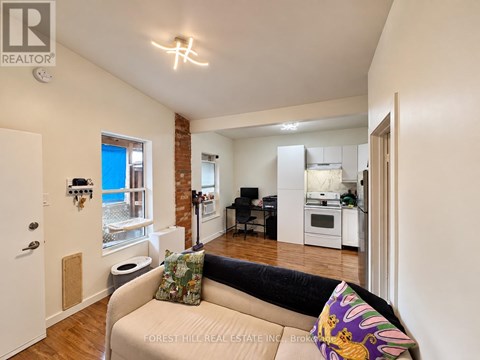 A living room with a couch and a kitchen area in the background.