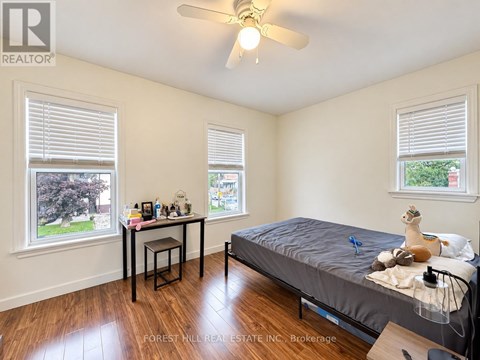 A bedroom with a bed, desk, and window.