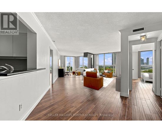 A modern living room with a kitchen area in the background.
