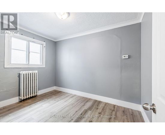 A room with a white radiator and wooden flooring.