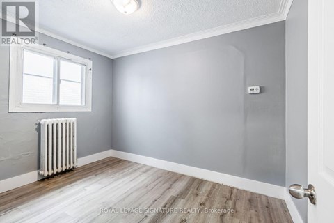A room with a white radiator and wooden flooring.