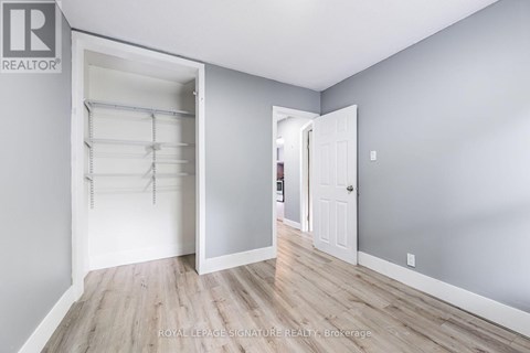 A white door is open to reveal a walk-in closet with shelves.