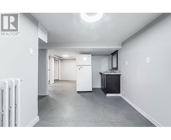 A spacious room with a white refrigerator and a black cabinet.