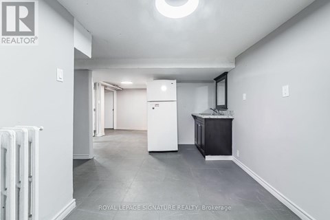 A spacious room with a white refrigerator and a black cabinet.