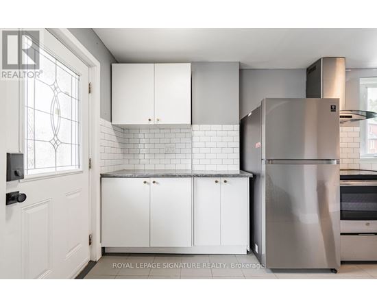 A kitchen with white cabinets and a stainless steel refrigerator.