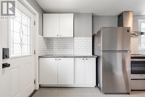 A kitchen with white cabinets and a stainless steel refrigerator.