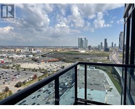 A view from a balcony overlooking a parking lot and city buildings.
