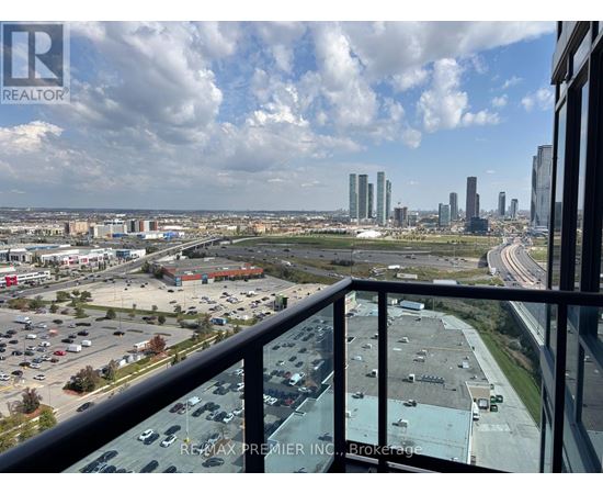 A view from a balcony overlooking a parking lot and city buildings.