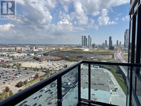 A view from a balcony overlooking a parking lot and city buildings.
