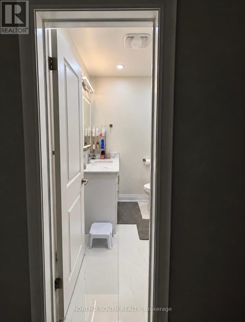 A bathroom with a toilet, sink and mirror.