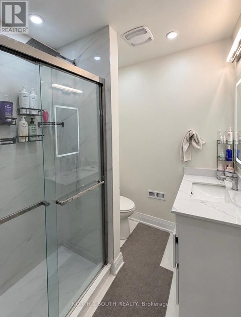 A bathroom with a glass shower door and a white sink.