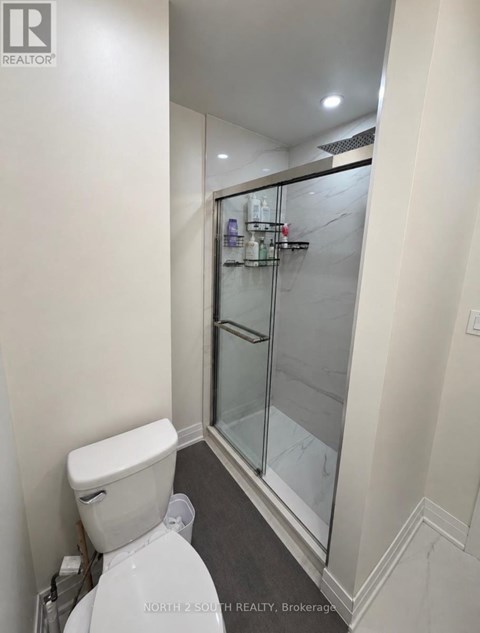 A white toilet in a small bathroom with a glass shower door.
