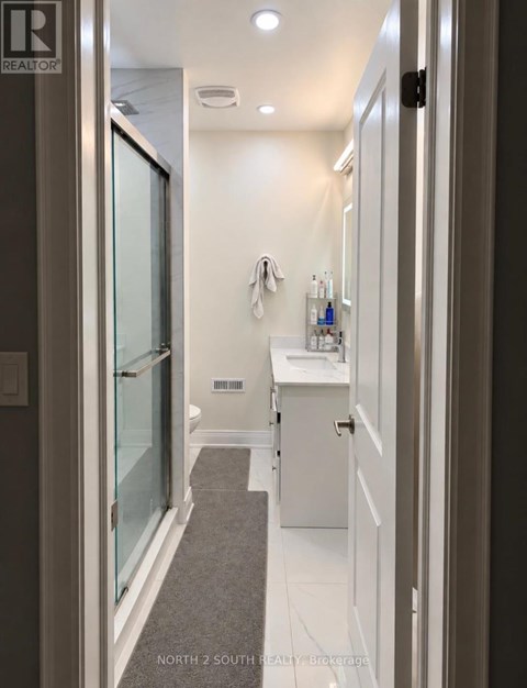 A bathroom with a glass shower door and white cabinetry.