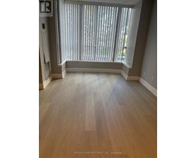 A room with a window covered in blinds and wooden flooring.