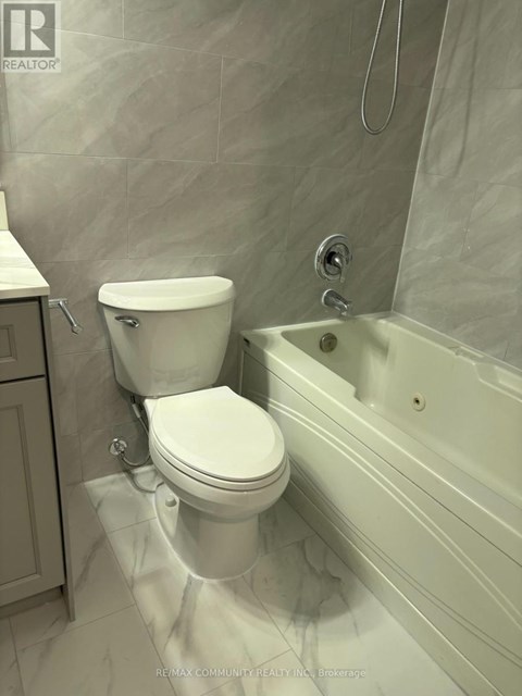 A white toilet sits next to a bathtub in a bathroom.