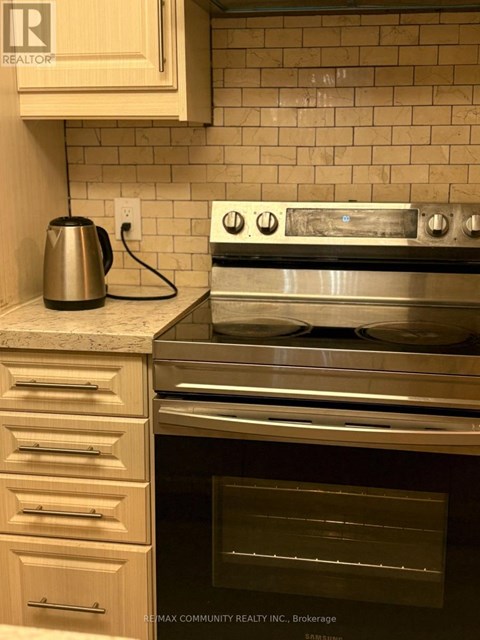 A modern kitchen with a stainless steel oven and a kettle on the counter.
