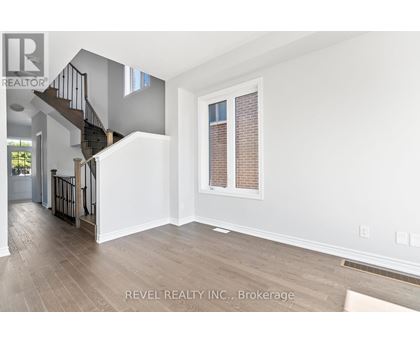 A spacious room with a staircase and a window with blinds.