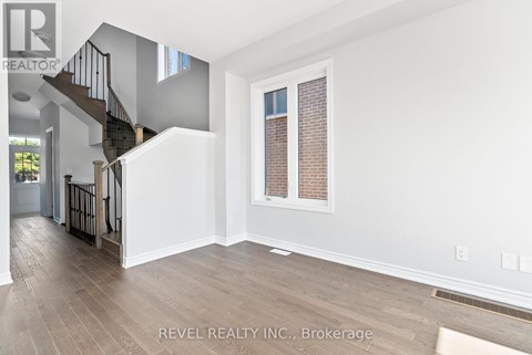 A spacious room with a staircase and a window with blinds.