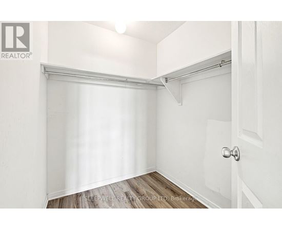 A white bedroom with a door and a window with blinds.