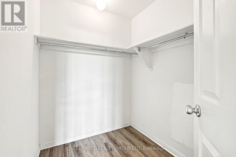 A white bedroom with a door and a window with blinds.