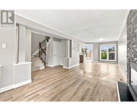A spacious room with wooden flooring and a staircase leading to another room.