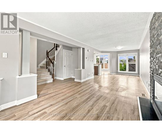 A spacious room with wooden flooring and a staircase leading to another room.