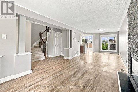 A spacious room with wooden flooring and a staircase leading to another room.