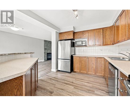 A kitchen with wooden cabinets and a stainless steel refrigerator.
