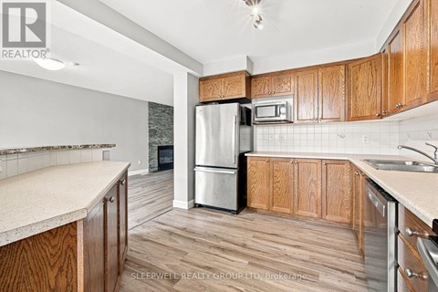 A kitchen with wooden cabinets and a stainless steel refrigerator.