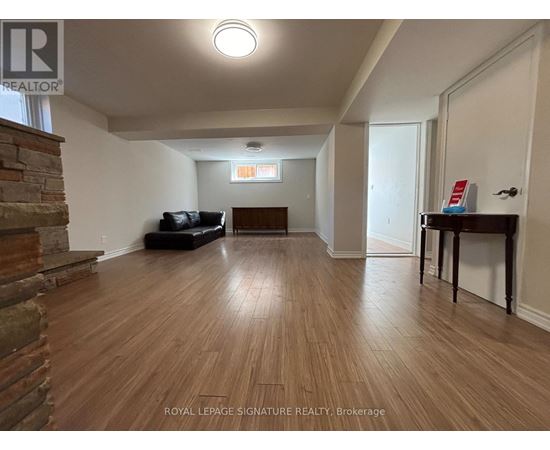 A living room with wooden floors and a stone fireplace.