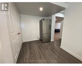 A white door is on the left of a room with a fridge.