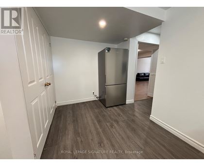 A white door is on the left of a room with a fridge.