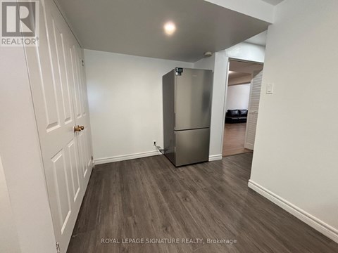 A white door is on the left of a room with a fridge.