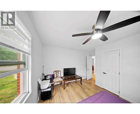 A room with a ceiling fan and a television.