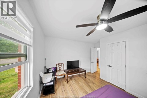 A room with a ceiling fan and a television.