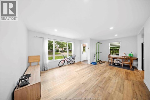 A spacious room with wooden flooring and a large window overlooking a garden.