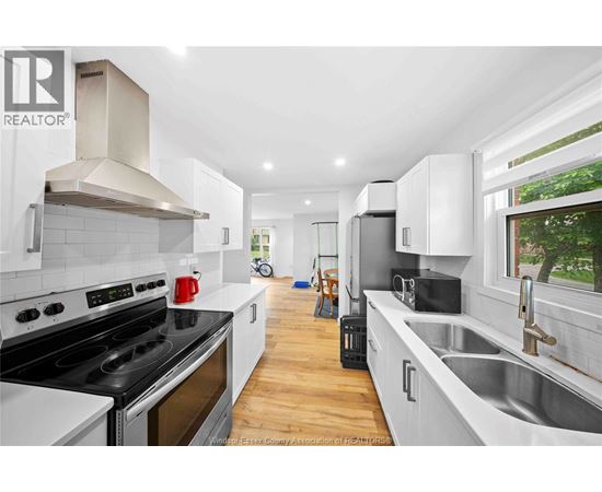 A modern kitchen with white cabinets and a black stove top oven.