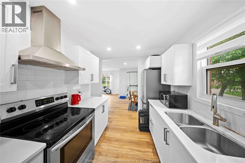 A modern kitchen with white cabinets and a black stove top oven.