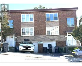A white car is parked in front of a brick building.