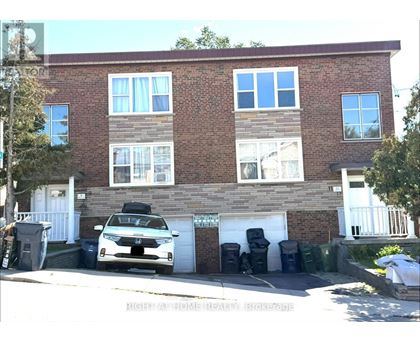 A white car is parked in front of a brick building.
